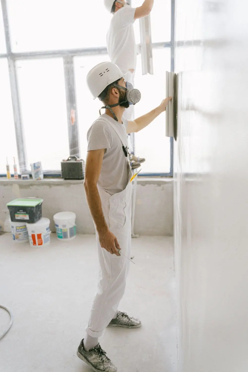 Stukadoor in witte overall werkt een wand glad